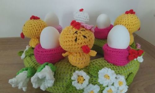 Ein gebastelter "Osterkranz" mit Eiern anstatt Kerzen, Stoffhühnern und Blumen 