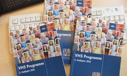 VHS Programmhefte liegen auf Tastatur