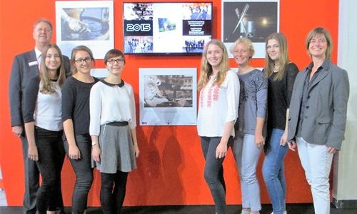 Schülerinnen des Ev. Gymnasiums, Frauke Mönkeberg und ein Mitarbeiter von Cewe vor einer Bilder Ausstellung