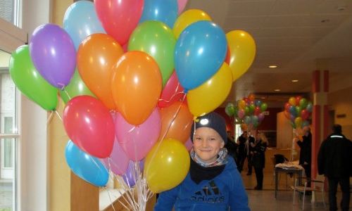 Kleiner Junge mit vielen bunten Luftballons